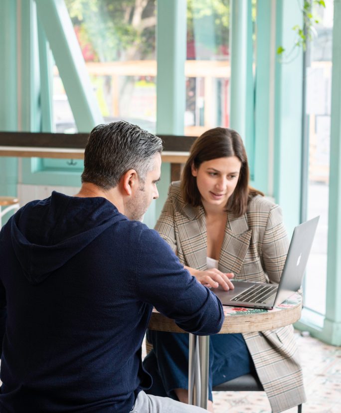 Deux employés regardent un ordinateur et discutent.