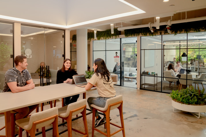 Three people sitting at a long desk in an office having a conversation